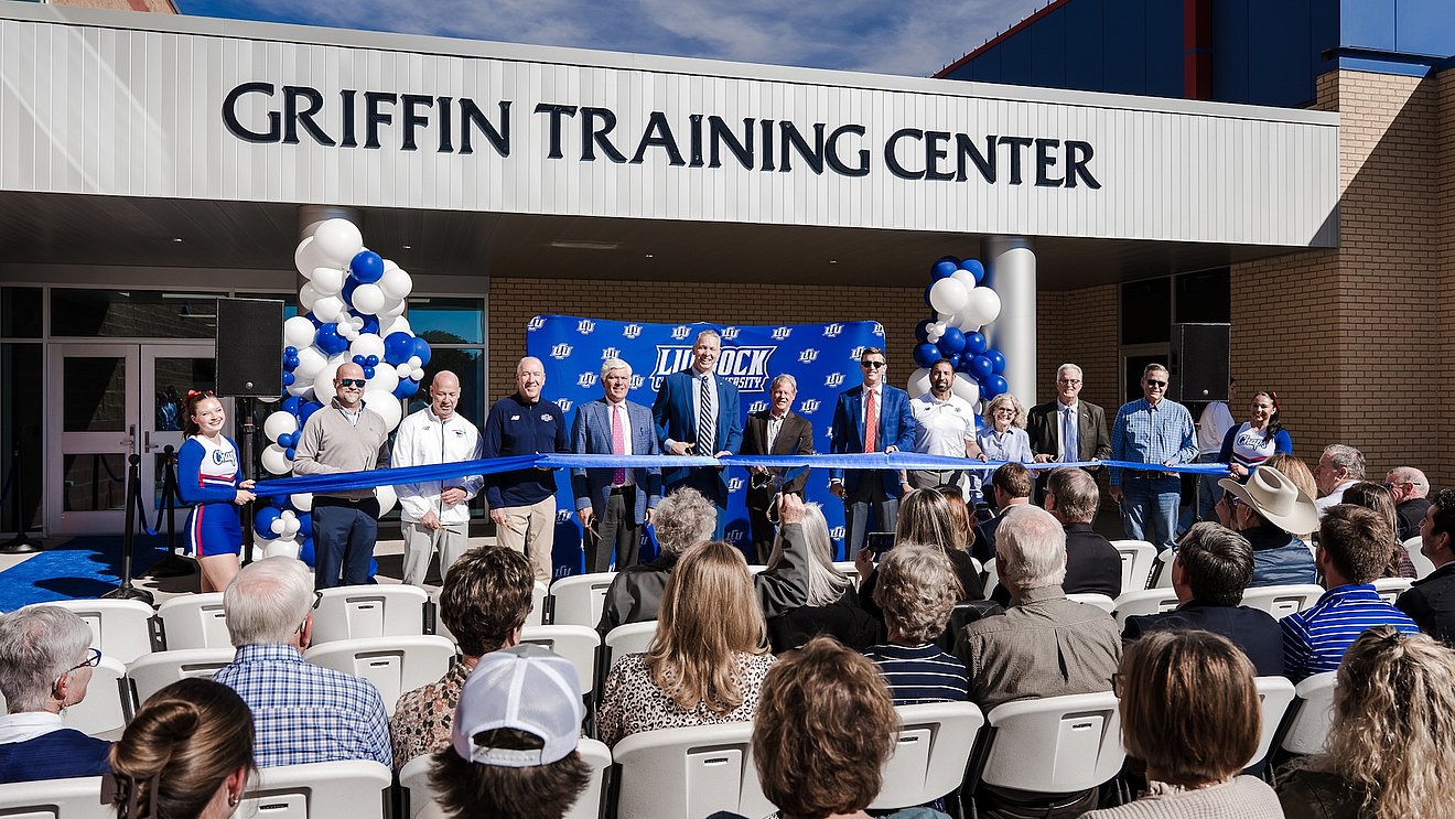 Photograph of LCU staff cutting a blue ribbon in front of the Griffin Training Center for a crowd of gathered supporters