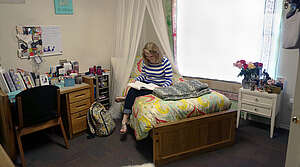 Girl sitting on a bed reading a book in a room
