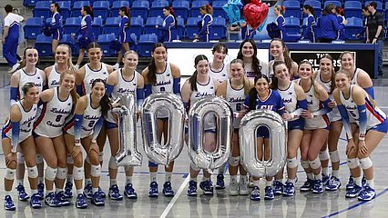 Photograph of LCU Volleyball team with big balloons with "1,000" on them.