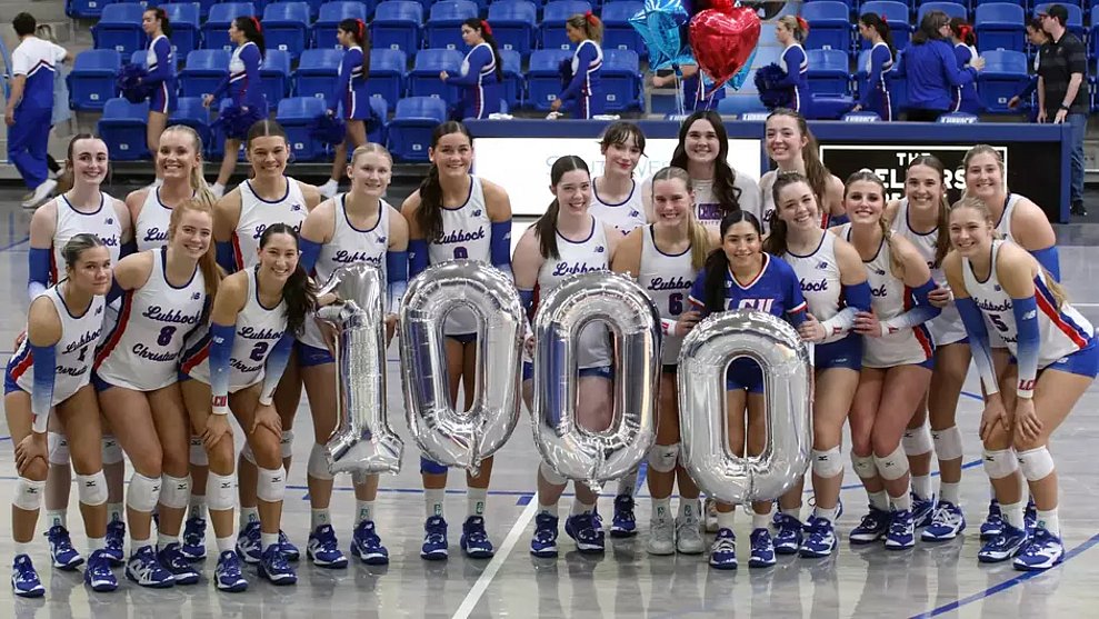Photograph of LCU Volleyball team with big balloons with "1,000" on them.