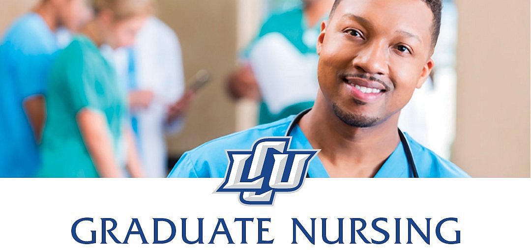 A man in blue nursing uniform smiling at the camera in front of an out of focus group of nurses