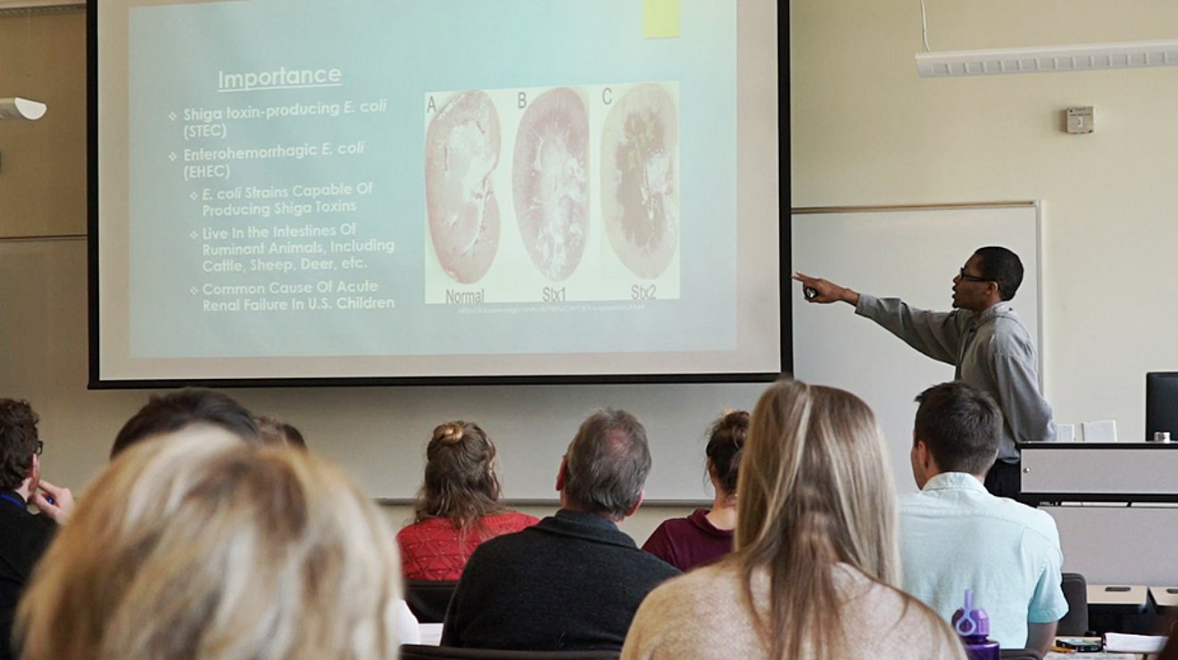 student presenting powerpoint slide in front of class