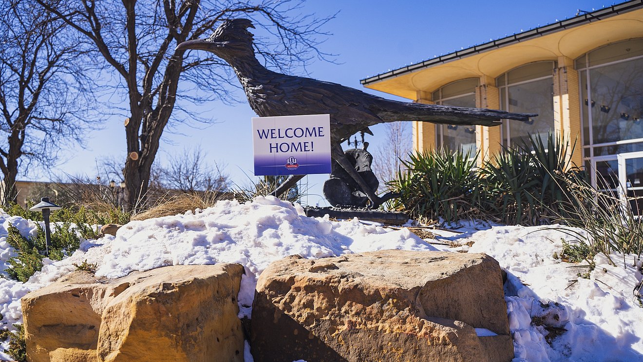 LCU's Chap statue standing amid snow with a sign saying, "Welcome Home!"