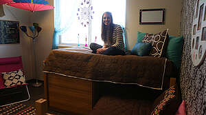 Girl sitting on lofted bed in dorm room