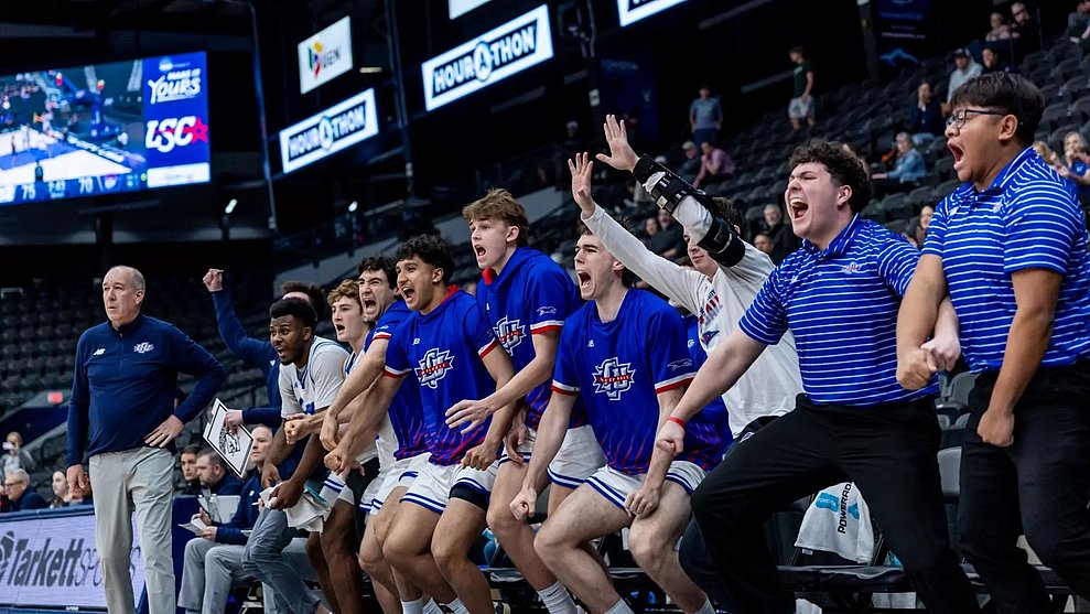 Photograph of the LCU basketball bench players all screaming victoriously during a close game in the LSC tournament