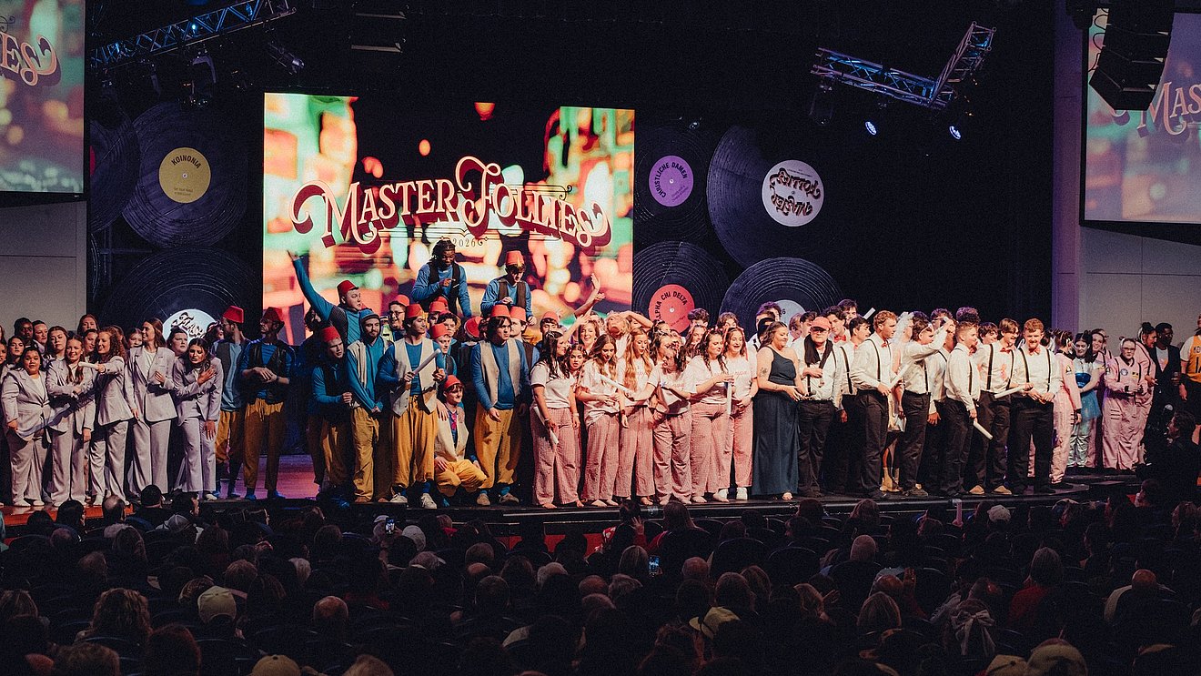 Photograph of the stage in the McDonald Moody Auditorium filled with the members of all of the social clubs as they await the results of Master Follies