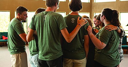 A few students standing in a group praying