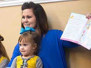 woman holding up book in children's bible class