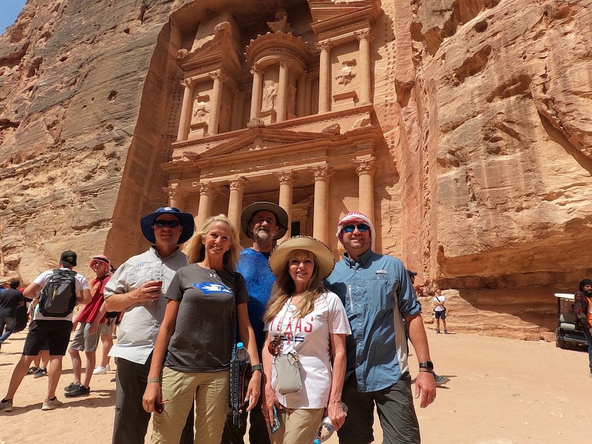 A group of five individuals standing together and posing in front of Al-Khazneh in Petra, Jordan