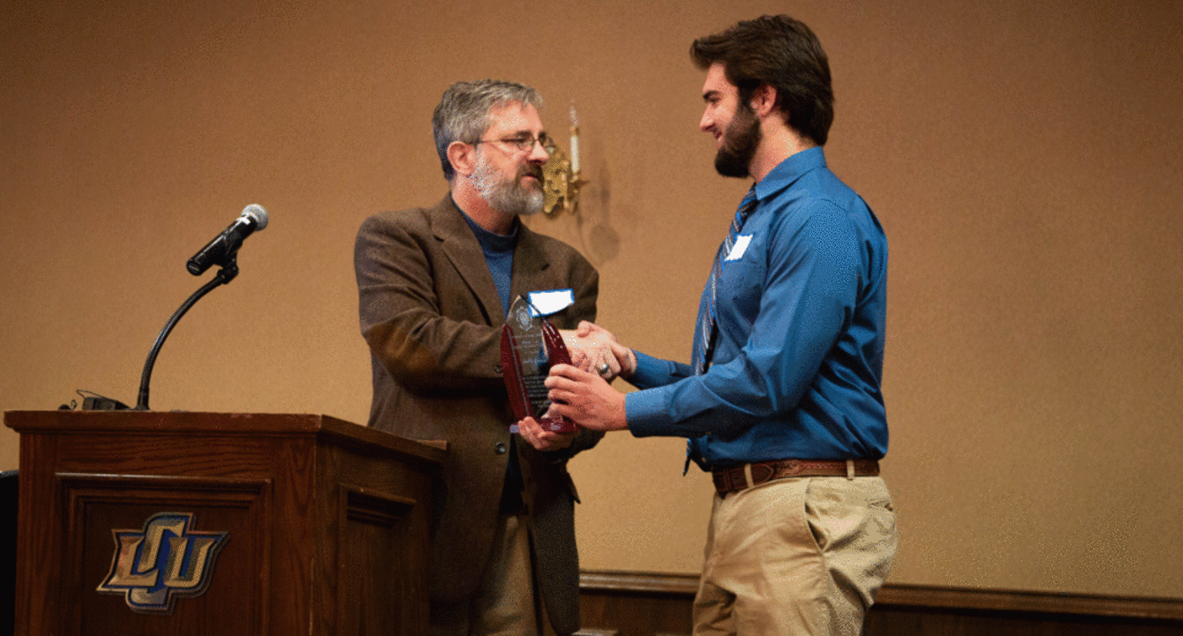 Dr. Brandon Fredenbug presents award to student