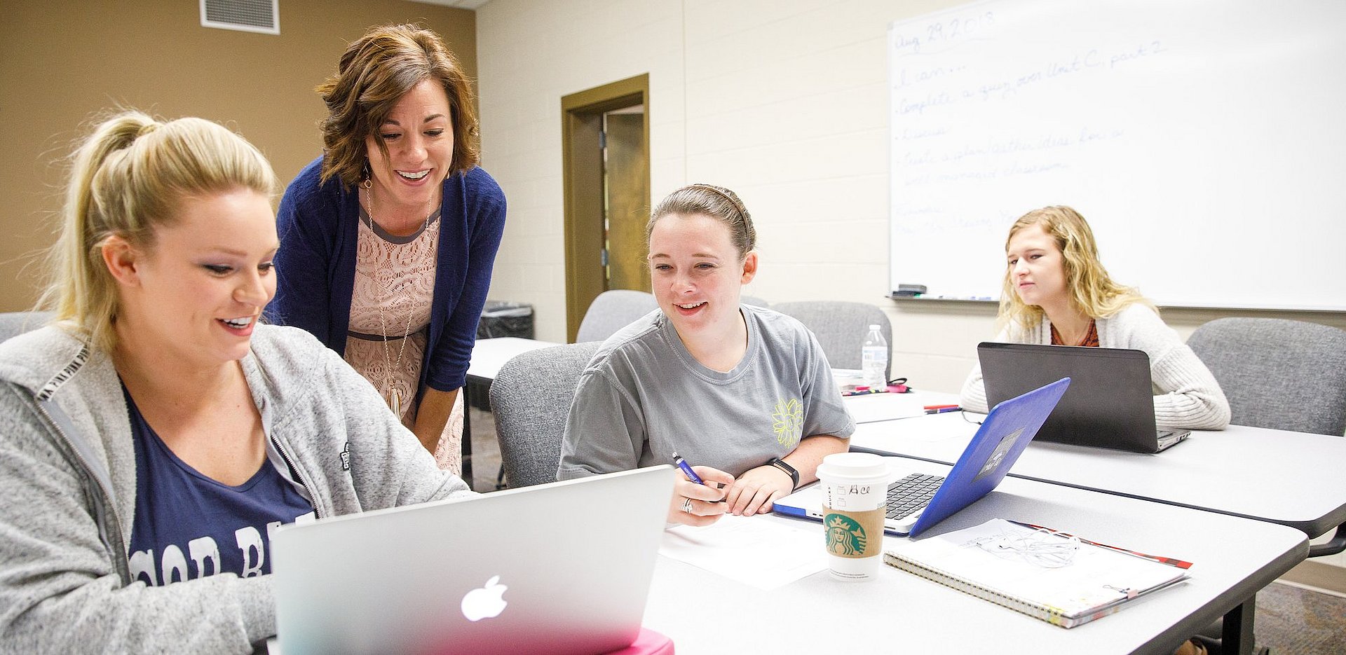 Students and professor looking at something on a computer