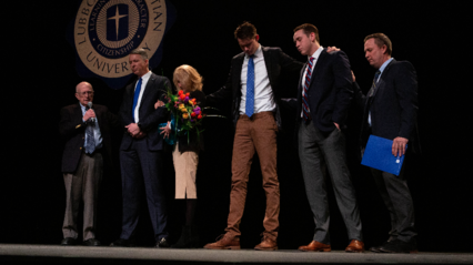 Dr. Steven Lemley, McDowell family, Randal Dement praying on stage