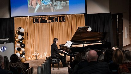Photograph of Maestro David Cho playing the piano on stage during the event