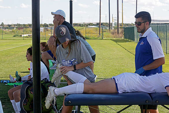 athletic trainer helping to stretch lcu soccer player
