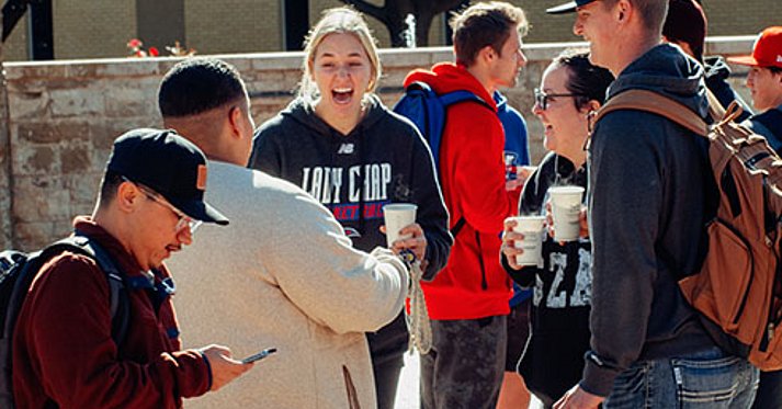 LCU students drinking hot chocolate around the fountain