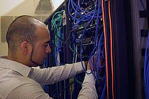 Man routing cables in a back of a server rack