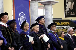 Administration standing in a line on stage during commencement