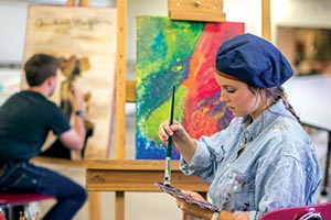 Girl mixing paint for a painting in art class