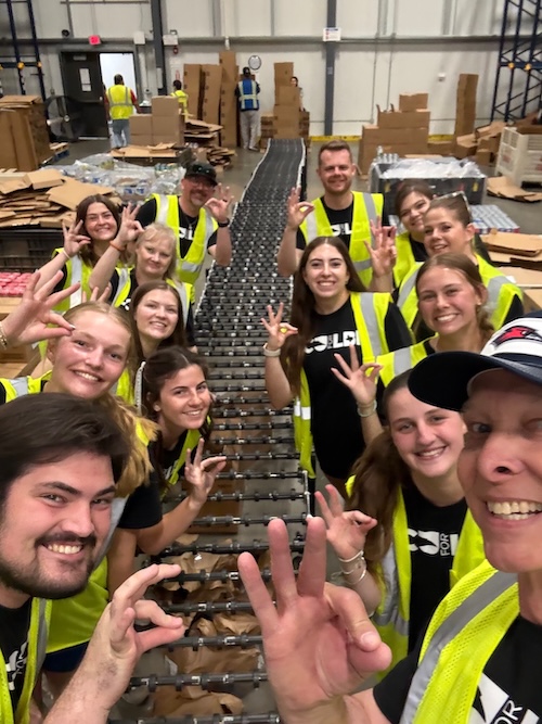 Photograph of LCU students, faculty, and staff members working together to assemble boxes on an assembly line at the Lubbock Food Bank
