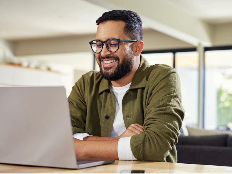 Man smiling at his computer screen working from home