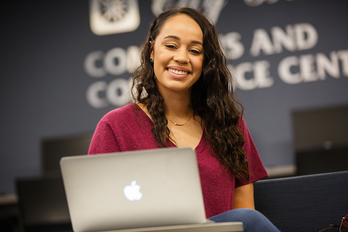 Business student smiling and working on a laptop in the business center