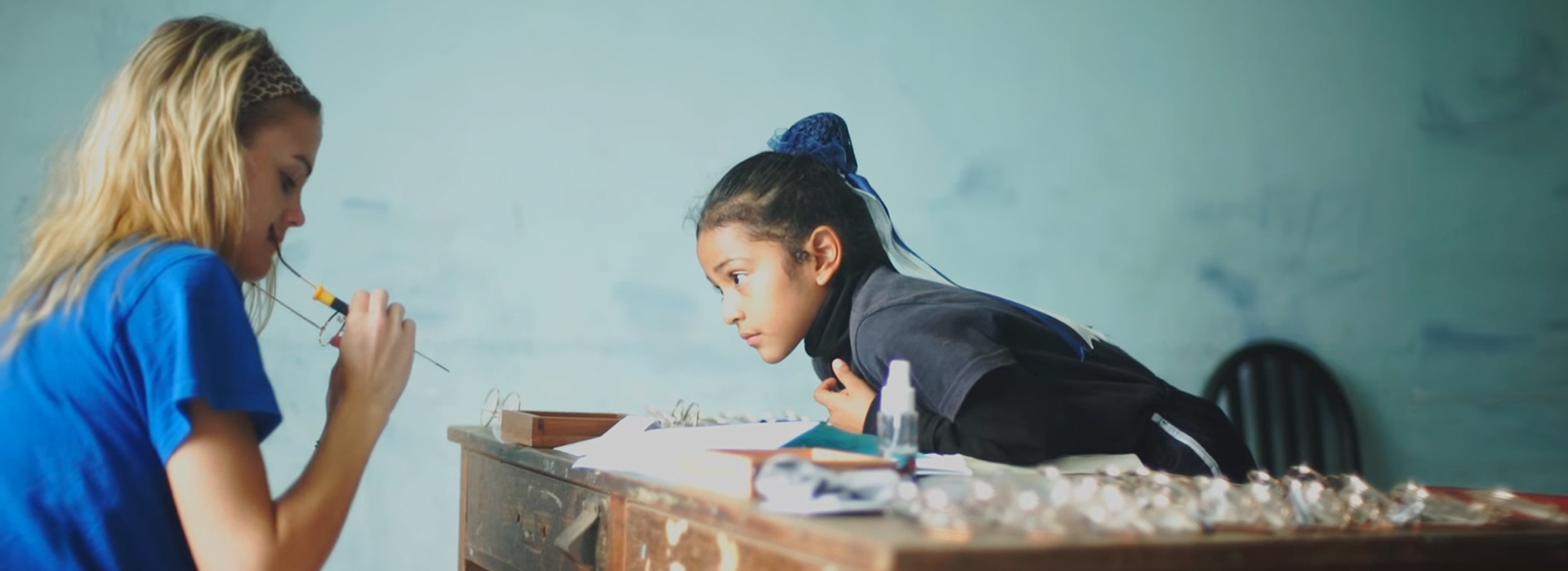 Student fixing glasses for little girl