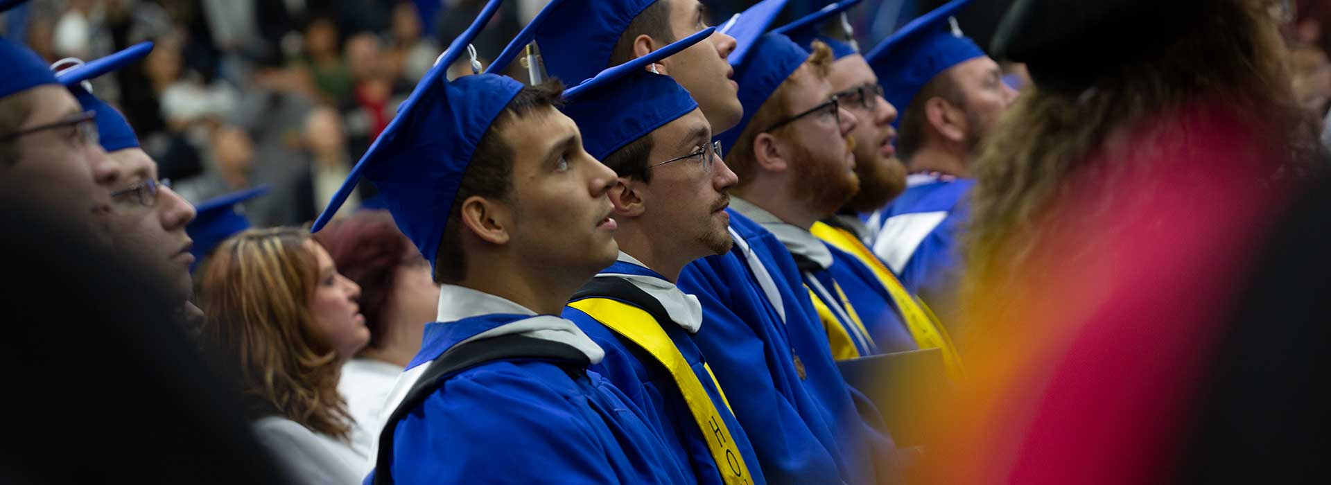 Students standing in a row watching the stage